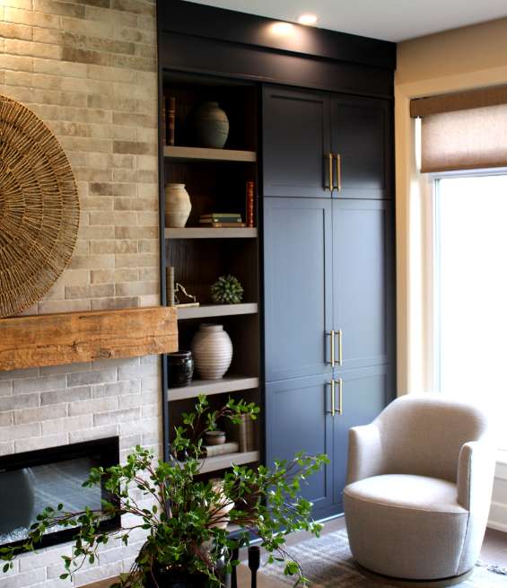 Navy cabinetry with gold hardware by an Ottawa cabinet manufacture next to a rustic brick fireplace.
