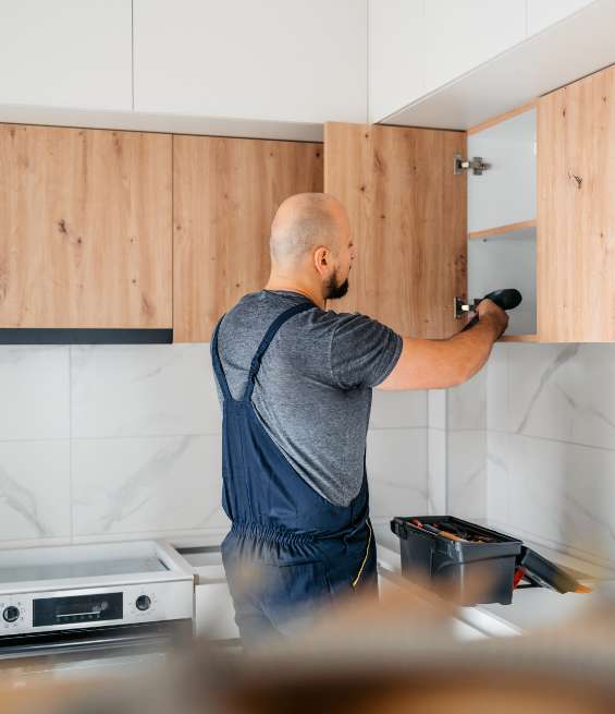 Technician installing kitchen storage units from a custom cabinet manufacturing facility in Ontario.